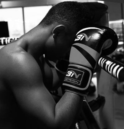 Person wearing boxing gloves with a brand logo in a gym setting